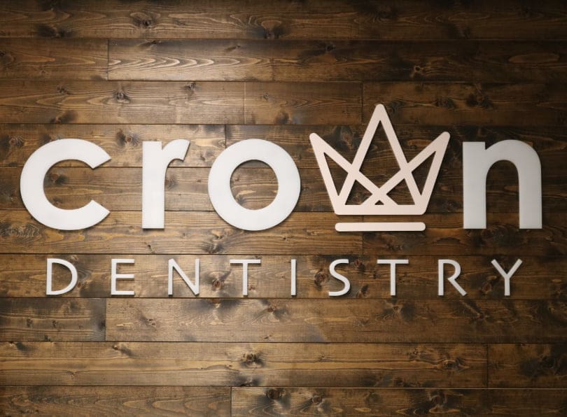 Crown Dentistry logo on a wood plank background